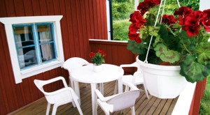 The red lakeside cottage has a small roofed terrace just in front of the house.