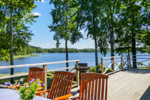 Der Blick von der Terrasse unseres Schweden Ferienhauses auf den See Saljen mit Booten und Badestelle.
